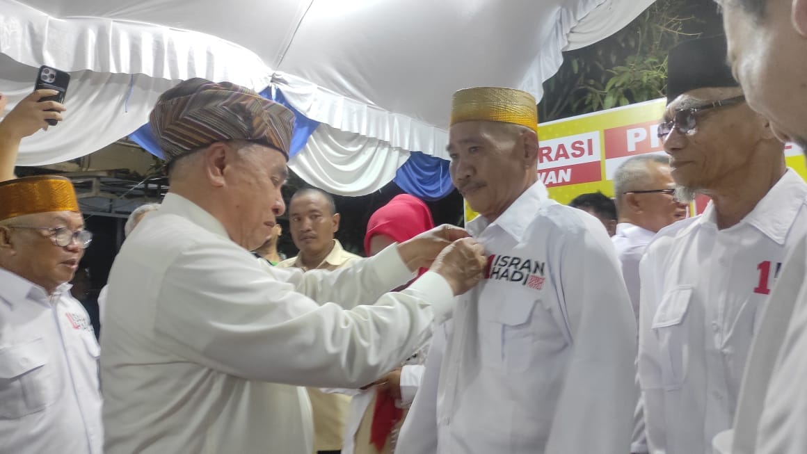 Calon Gubernur Kaltim Isran Noor memakaikan seragam relawan Isran-Hadi kepada Daeng Tunru pada Senin malam (14/10/2024).
